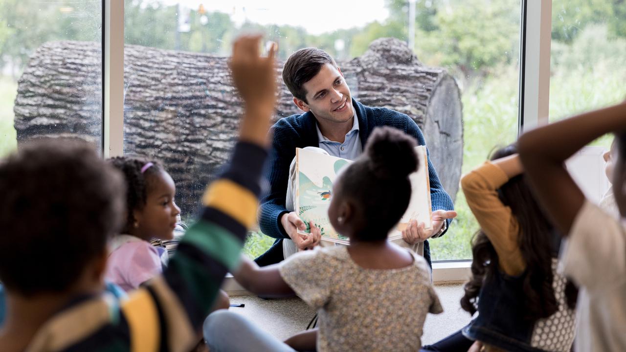 Confident kindergarten teacher or parent reads to a group of children.