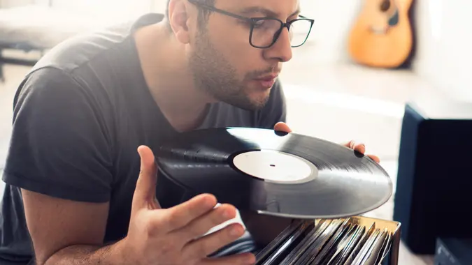 Young guy is cleaning dust from his vinyl records.