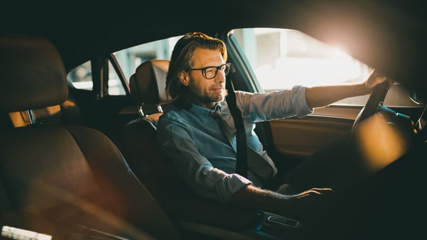 Close up photo of a businessman driving a car.