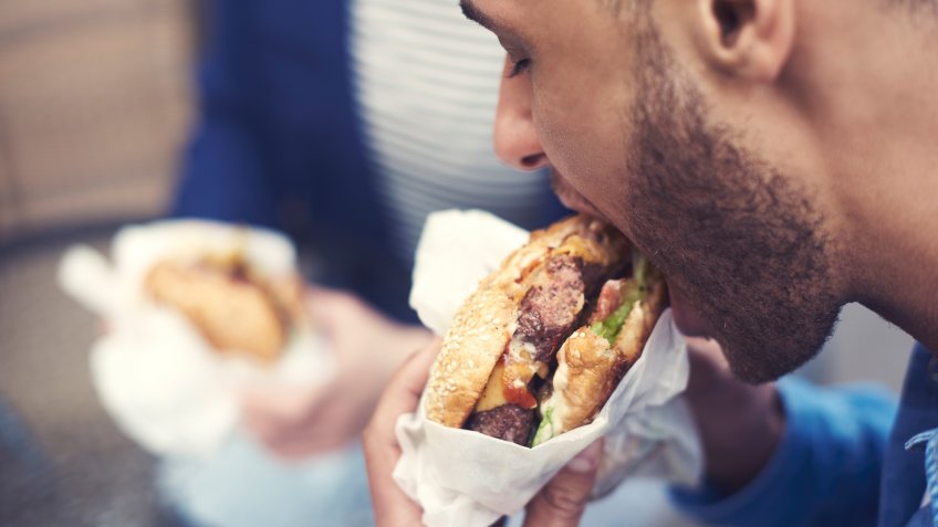 Close up of man eating cheeseburger.
