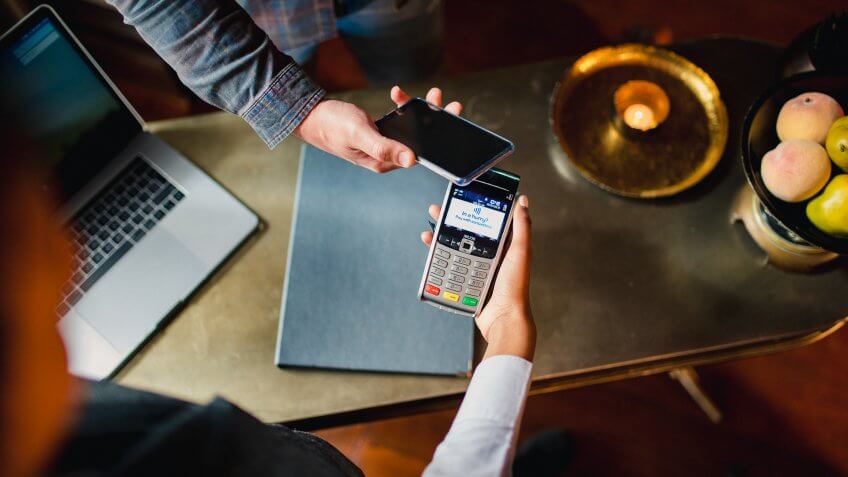 A close up, directly above shot of a man paying with his mobile phone on a credit card reader.