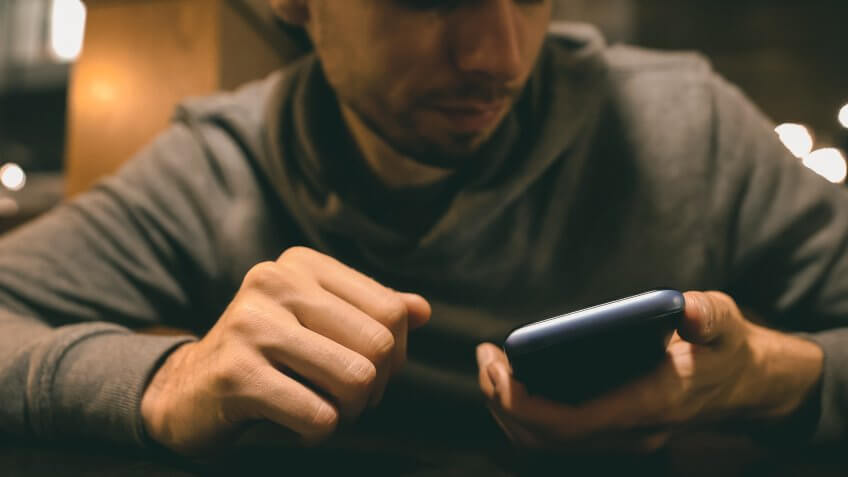 Angry man looking at phone, receiving bill from bank after party, credit card.