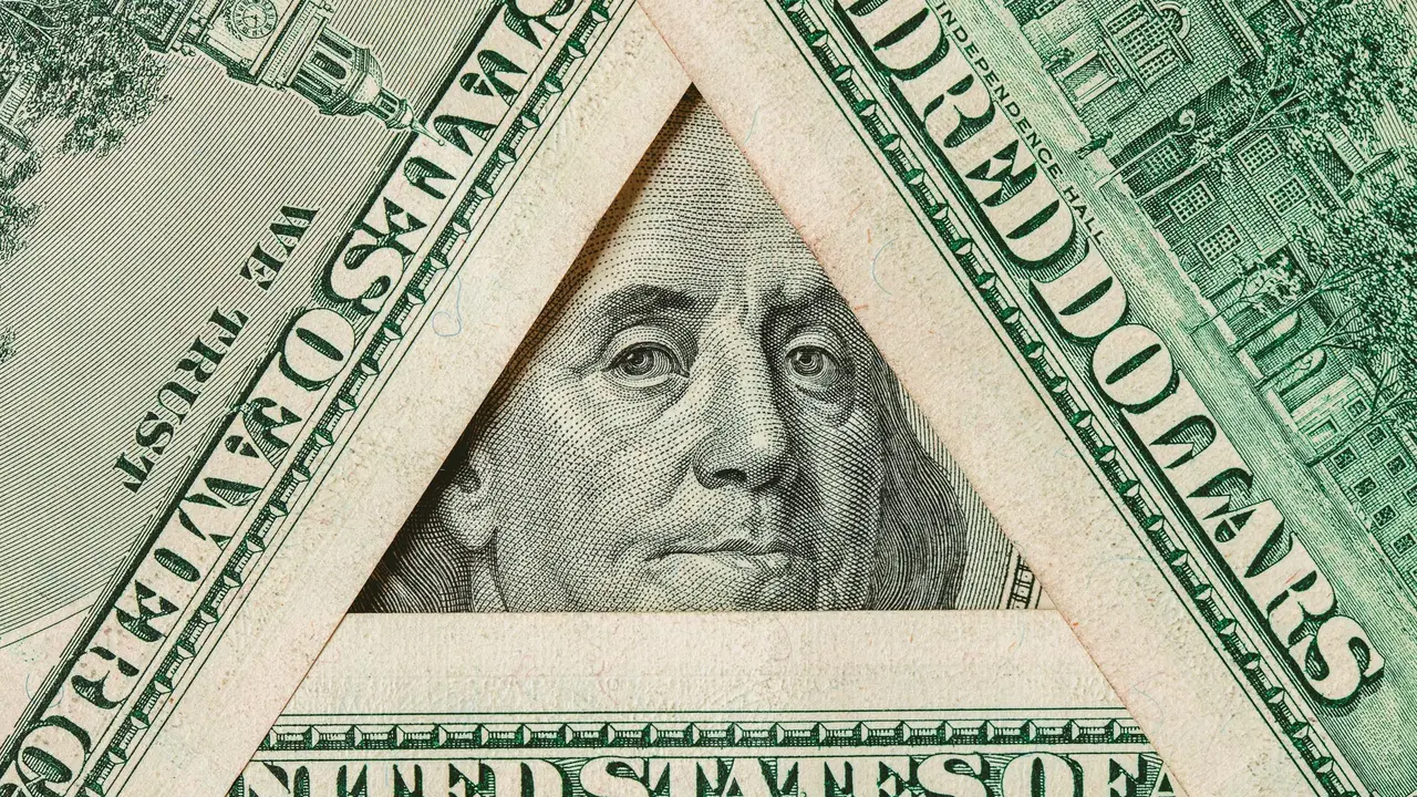 Triangle made of $100 banknotes with Benjamin Franklin portrait inside.