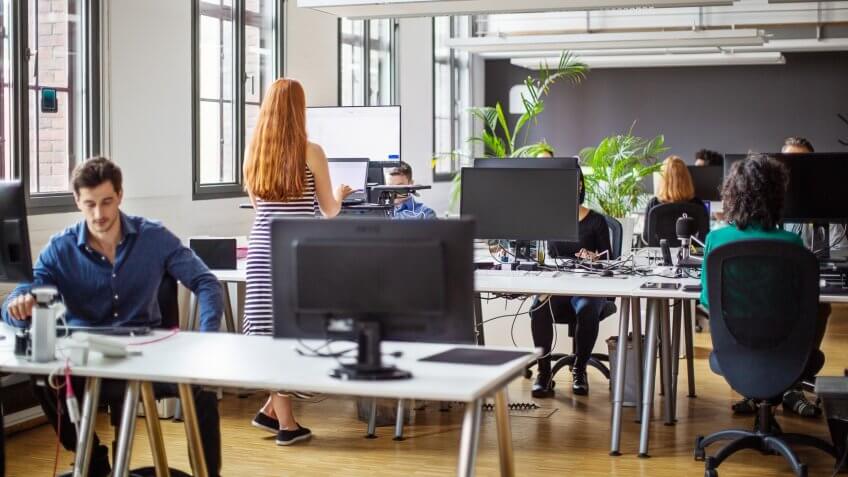 Business colleagues working at a busy open plan office.