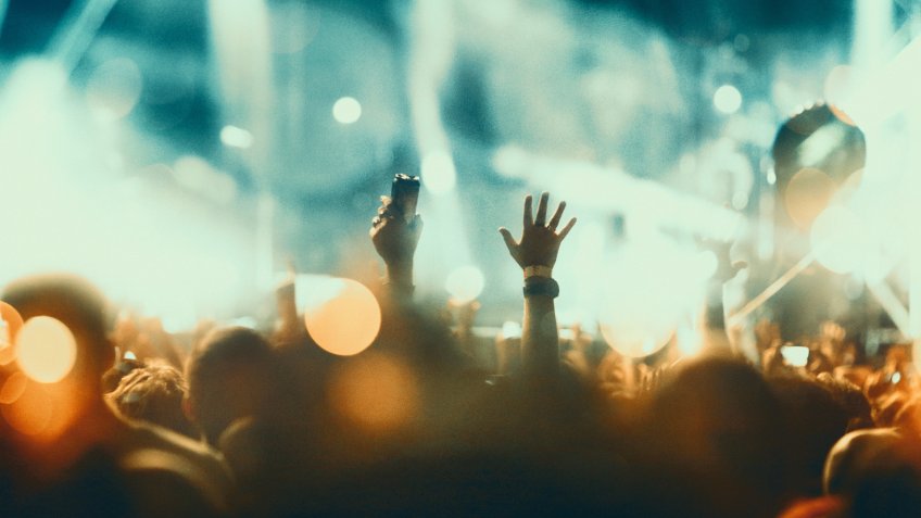 Rear view of large group of unrecognizable people enjoying a concert.