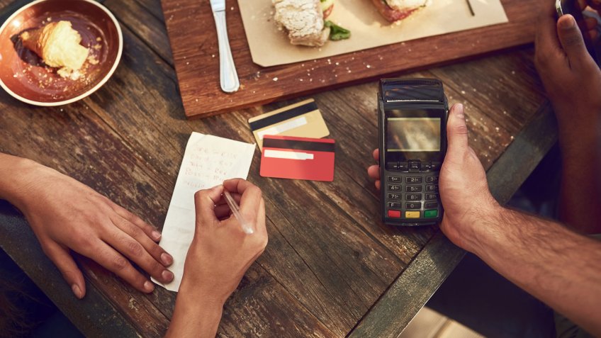High angle shot of an unrecognizable man ready to pay the bill with his credit card at a cafe.