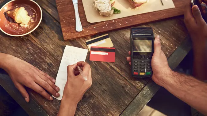 High angle shot of an unrecognizable man ready to pay the bill with his credit card at a cafe.