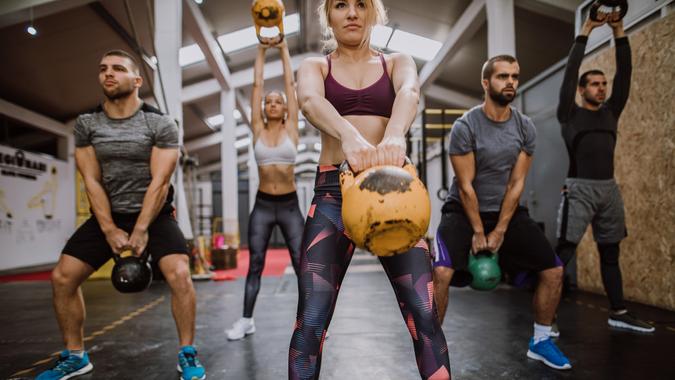 Athletes squat with kettlebells during fitness training.