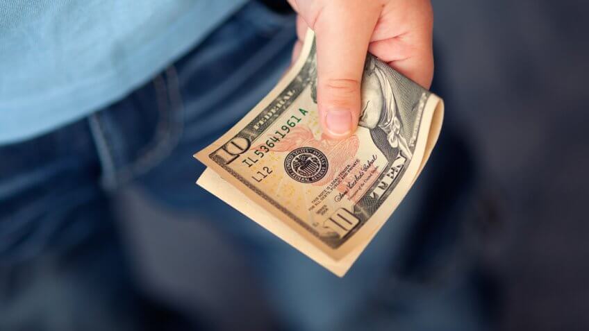 Young boy holds ten dollars.