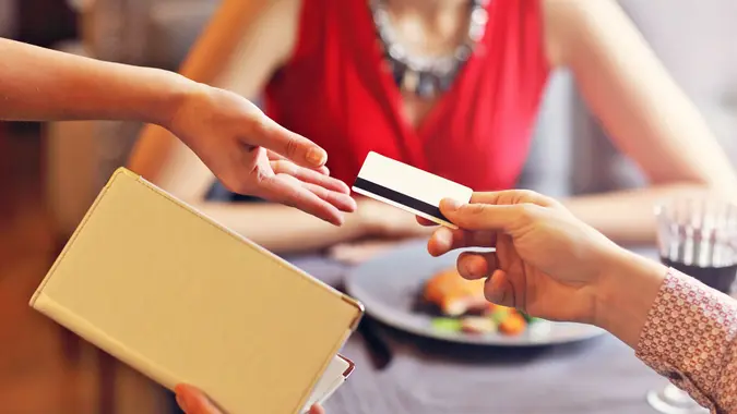 Picture showing people paying in restaurant by credit card reader.