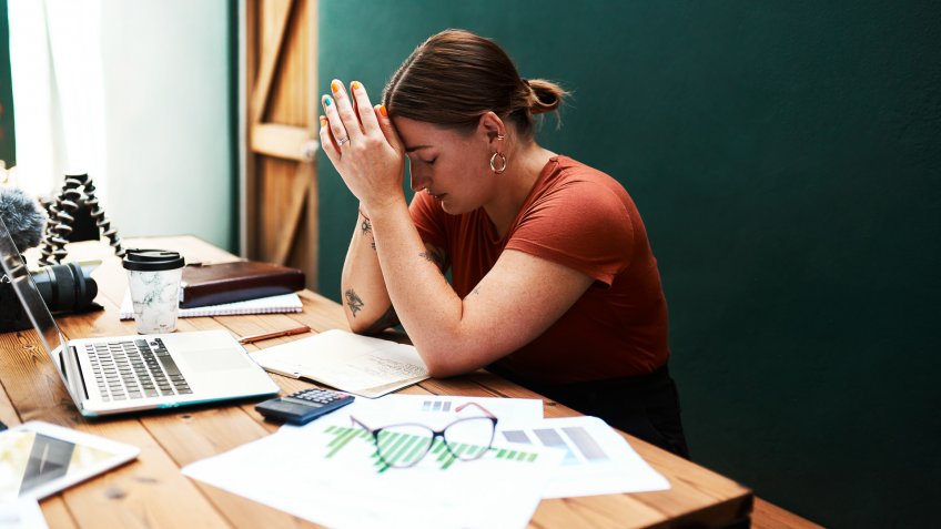 Cropped shot of an attractive young businesswoman sitting alone at her desk and suffering from a headache.