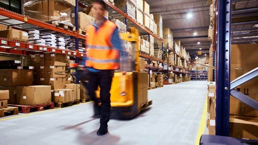 Warehouse, worker with a forklift in motion blur.