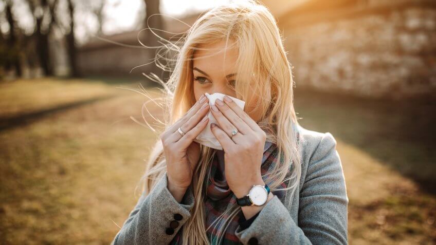 Sick blonde blowing her nose.