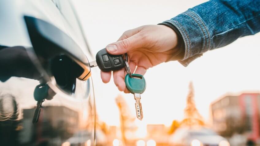 Unrecognizable woman opening her car with a key.