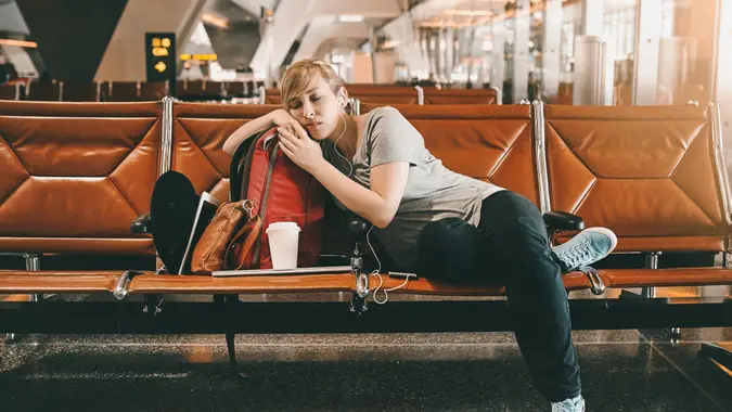 Full length shot of an attractive young woman sleeping in an airport.