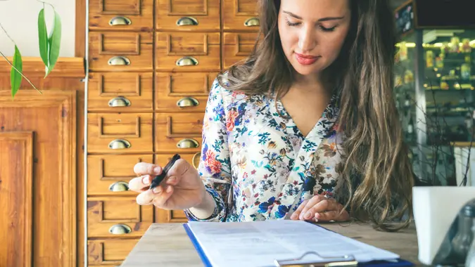 Beautiful businesswoman signing contract in a cafe indoors.