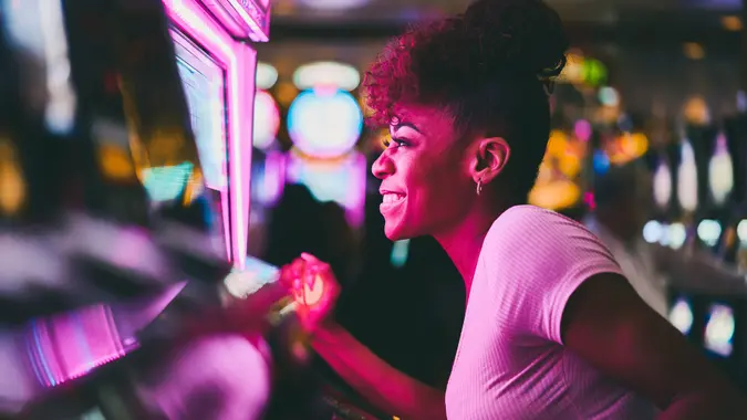 woman having fun playing slot machine at casino pulling lever.