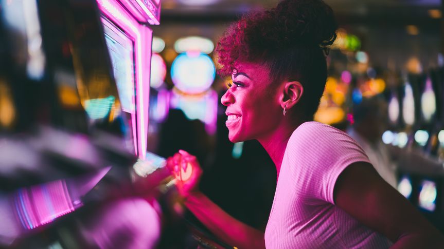 woman having fun playing slot machine at casino pulling lever.