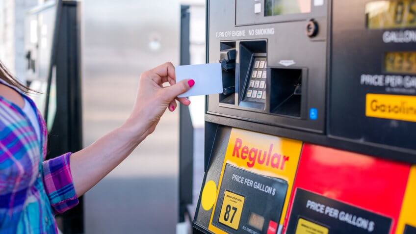 Female hand inserting credit card into petrol machine.