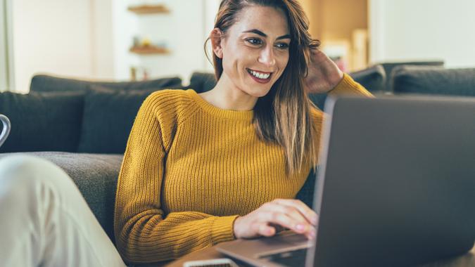 Young beautiful woman using laptop, surfing internet and relaxing at home.