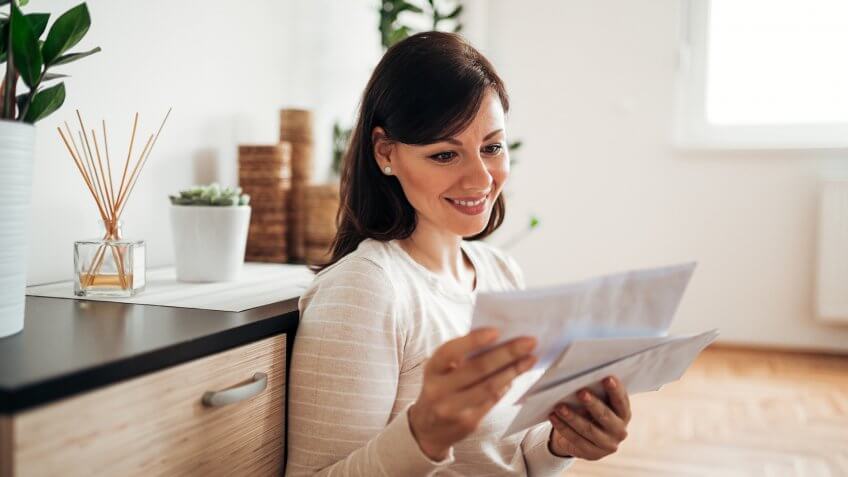 Beautiful woman looking at mail at cozy home.