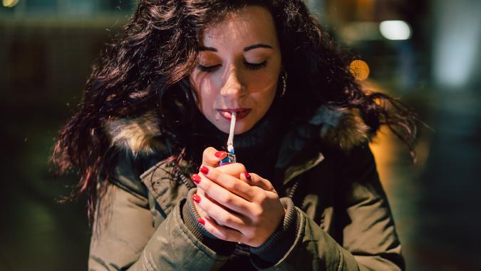 Young Adult Woman Lighting Cigarette In The City At Night.