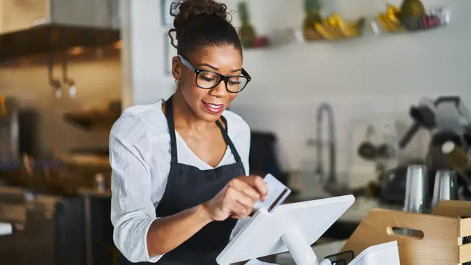 friendly waitress swiping bank card on pos terminal in restaurant during the day.