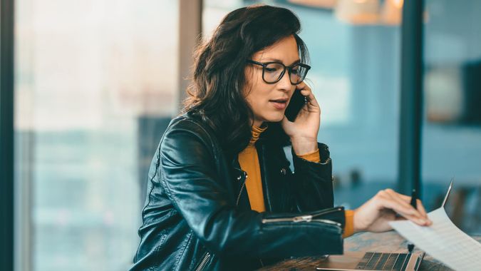 Asian business woman talking on cell phone while working at office.