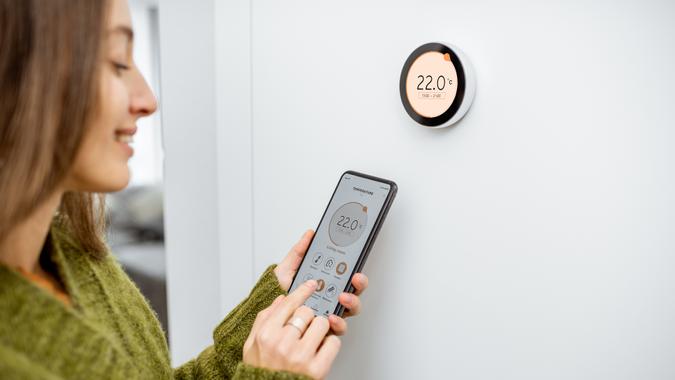 A woman adjusting her thermostat with her phone