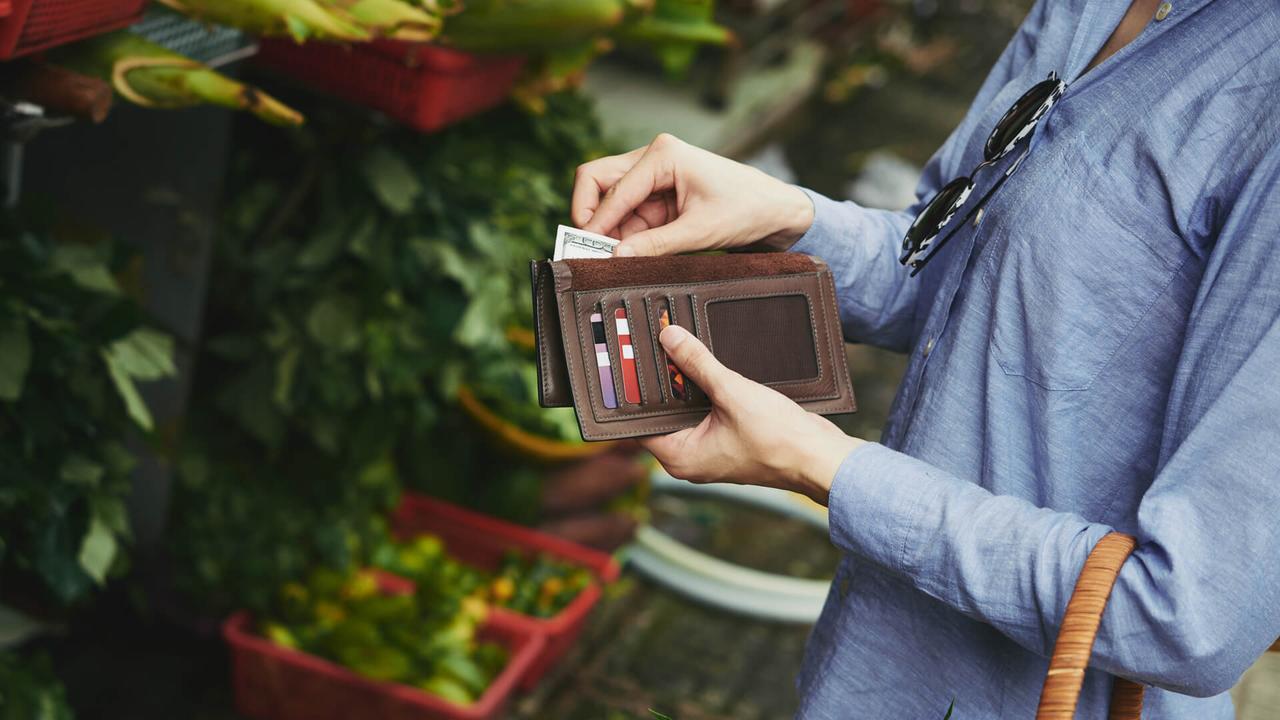 Woman taking money out of wallet to pay for the vegetables.