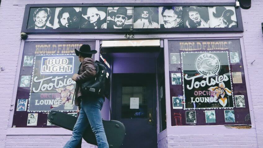 Mandatory Credit: Photo by Mark Humphrey/AP/Shutterstock (10585114i)Man walks by Tootsie's Orchid Lounge, closed because of the coronavirus, in Nashville, Tenn.