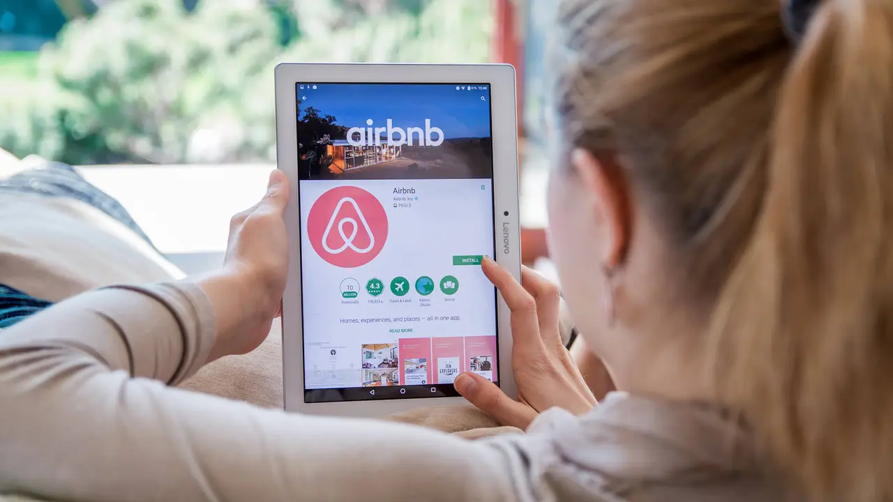 Someone on an iPad booking an Airbnb home rental service