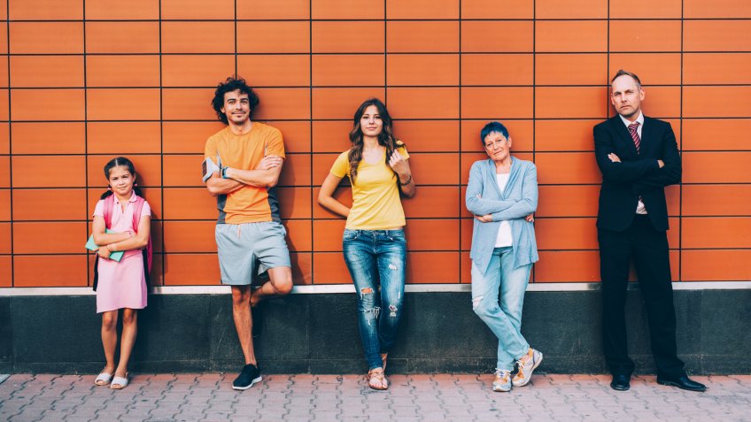 Five people at different ages standing agains a wall seperately.