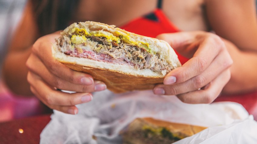 Cuban sandwich closeup woman holding local food at typical cafe outside.