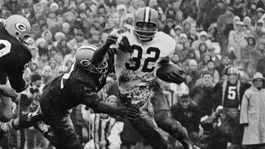 Cleveland Browns' Jim Brown (32) turns the corner as a Green Bay Packer defender swings with him during a football game in Green Bay, Wisc.