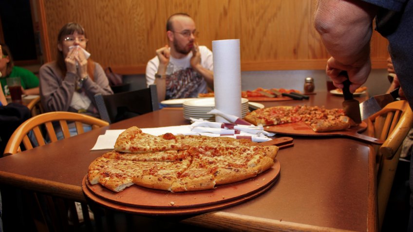 A shot of Pizza thats for supper on a table thats sliced on a plate thats ready to eat.