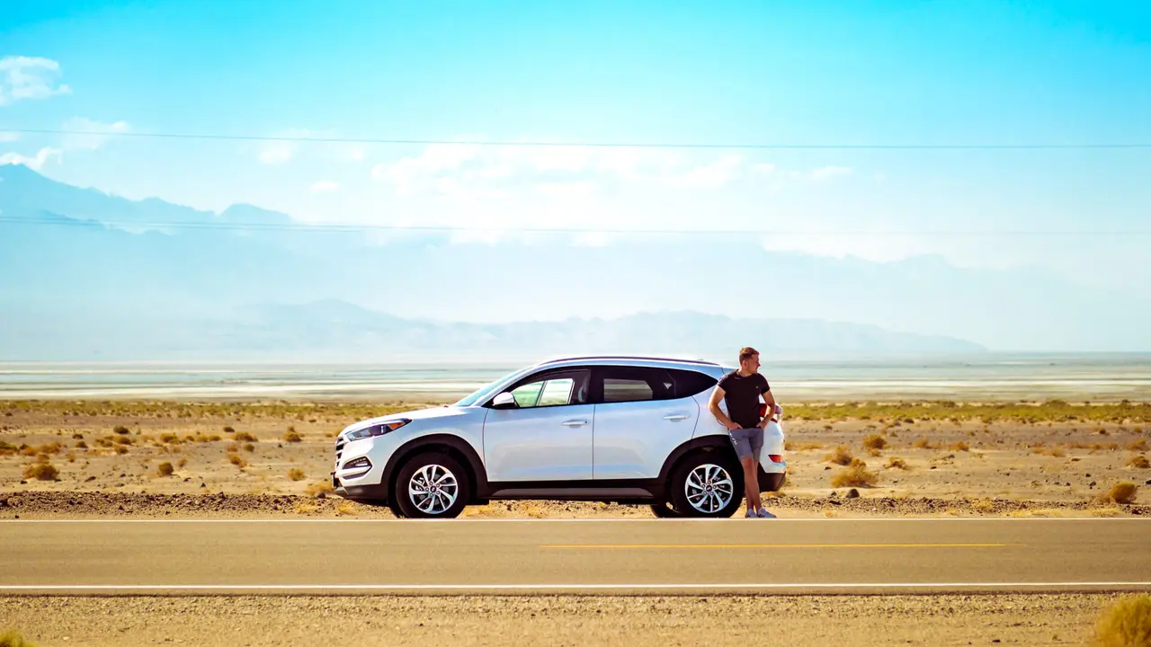 Man standing next to car in desert highway