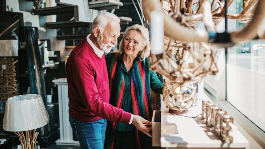 Senior couple in home lighting store shoosing shandelier for their home.