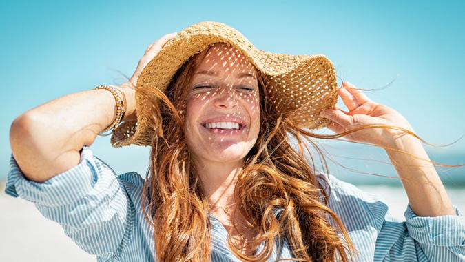 Closeup face of mature woman wearing straw hat enjoying the sun at beach.