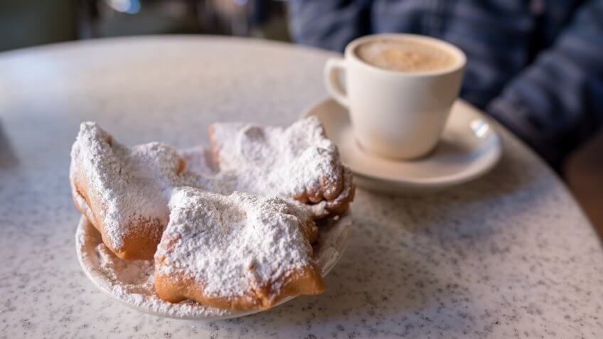 New Orleans, LA, January 25, 2018: Beignets covered with powdered sugar, served with cafe au lait at the famous Cafe Du Monde in the French Quarter.