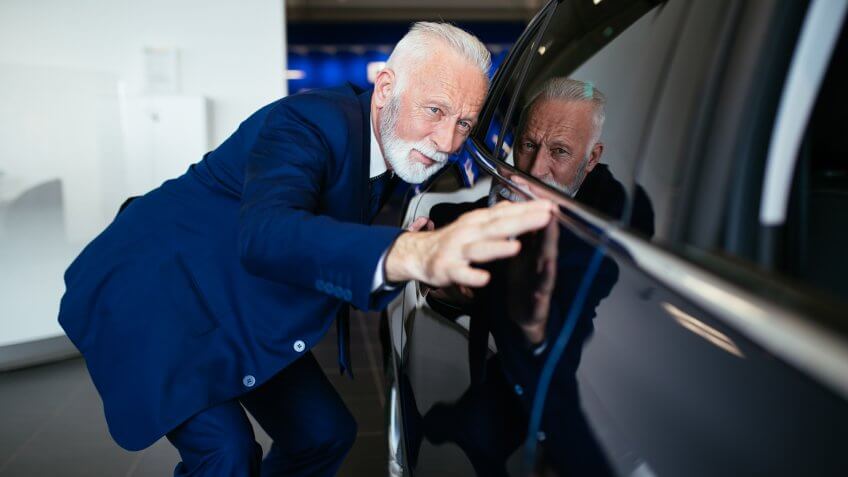 Senior man choosing a new car at car showroom.