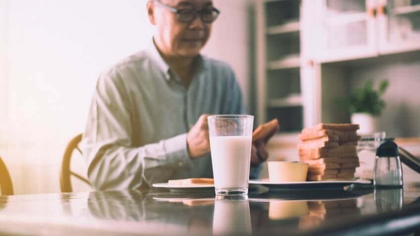 Blurred of asian elderly couple preparing healthy food for breakfast with bread and butter,Retirement senior lifestyle living concept.