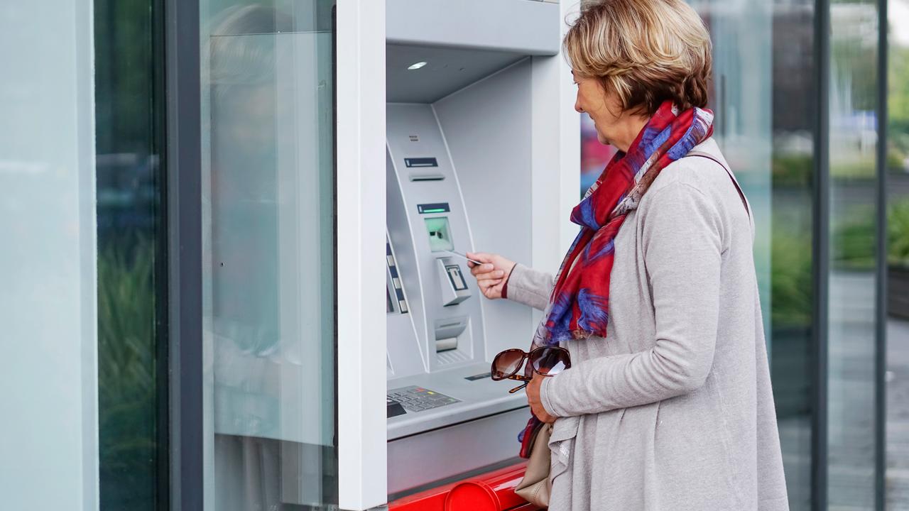 Senior woman using ATM in the city.