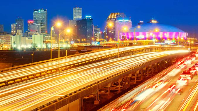 City skyline photo of New Orleans Louisiana USA with traffic on highways, downtown skyscrapers and the Superdome, shot at twilight blue hour.