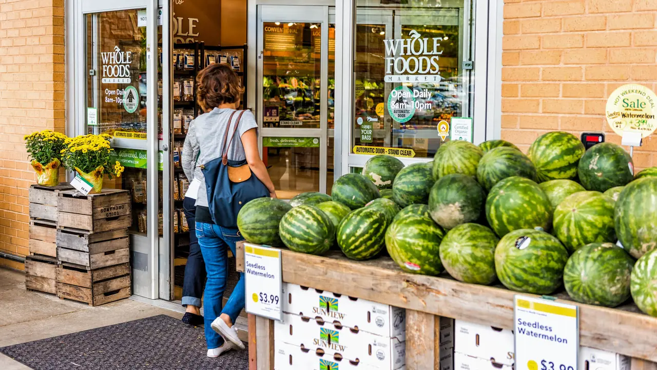 Fairfax, USA - September 8, 2017: female entering Whole Foods Market grocery store building in city in Virginia with autumn displays and watermelons.