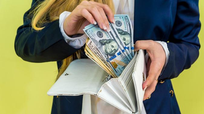Female takes out dollar from wallet.