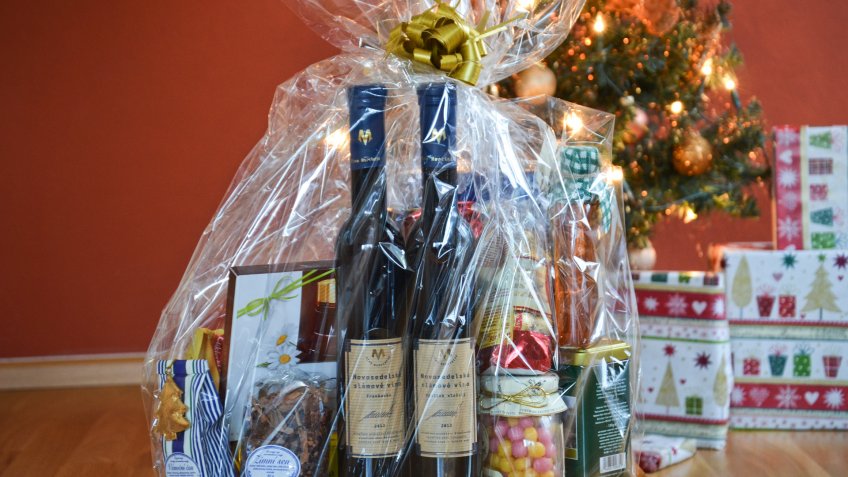 Pilsen, Czech Rep - Dec 24th 2016: Wrapped food basket with delicacies as one of the Christmas gifts in front of the lighting Christmas tree.