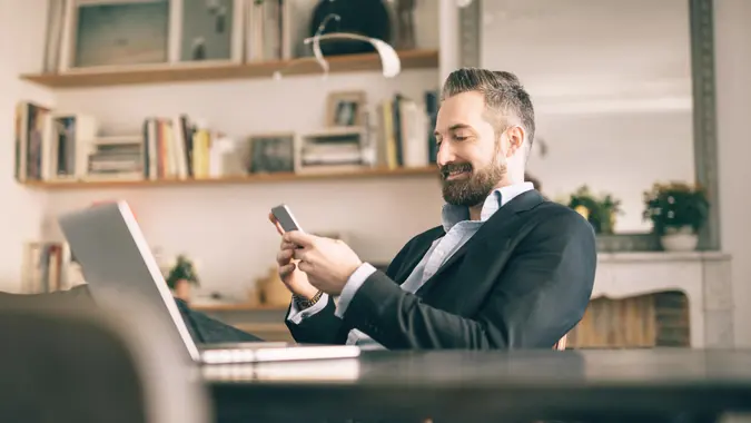 bearded man using smartphone in homeoffice.