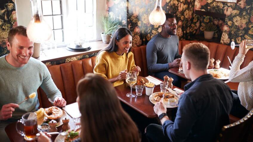 Group Of People Eating In Restaurant Of Busy Traditional English Pub.
