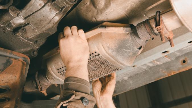 A SUV's catalytic converter is being removed at a salvage yard.